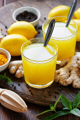 Immune booster antivirus drink, turmeric with ginger, lemon, mint and spices hot winter tea on wooden rustic background, closeup, natural medicine and naturopathy concept