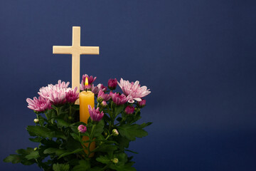 Composition of burning candle, flowers and wooden cross for all souls day. Also suitable for...