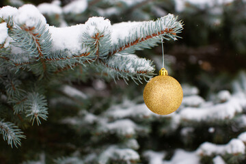 Fototapeta na wymiar Gold Christmas tree ornament on snowy tree