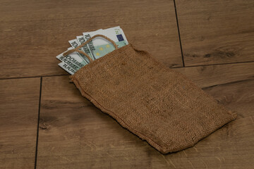 Banknotes of 100 euros in a bag on a wooden background. Piggy bank for purchases.