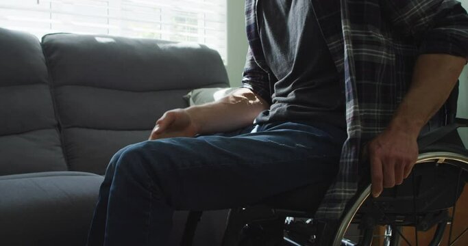 Caucasian disabled man in wheelchair sitting on sofa in living room