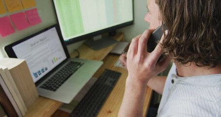 Focused caucasian man working remotely, using laptop and talking on smartphone