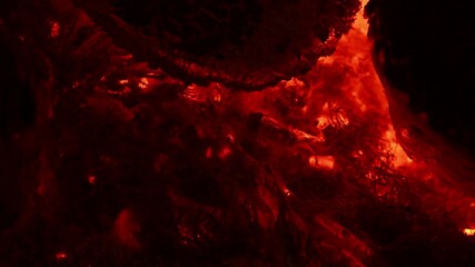 Incandescent orange and red embers texture. Contains the sound of crackling and chirping crickets. Side view. 4K UHD video footage 3840X2160