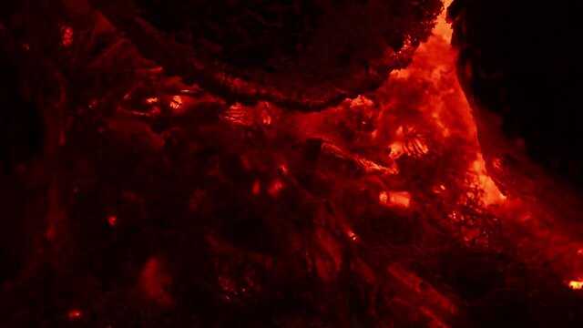 Incandescent orange and red embers texture. Contains the sound of crackling and chirping crickets. Side view. 4K UHD video footage 3840X2160
