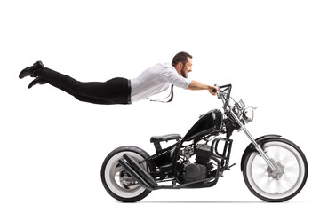 Obraz na płótnie Canvas Man holding onto a chopper motorbike and flying