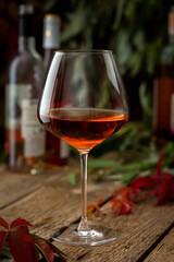 Autumn cozy romantic evening outdoors, wooden table with glass with rose wine and bottles of wine