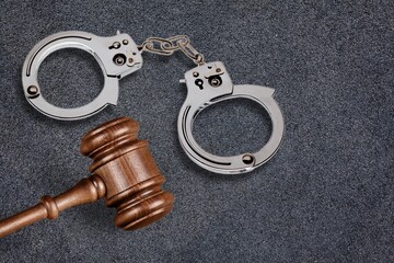 Handcuffs and wooden gavel on the desk. Crime and violence concept.
