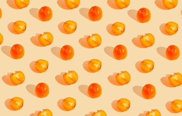 Creative pattern made of persimmon fruits on pastel background with sunlit. Healthy food concept
