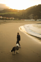 young girl walking on the beach with her dog old english sheepdog