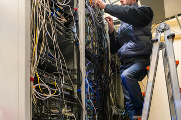 Maintenance of network Internet equipment in the data center rack.The technician is laying the...