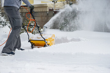 Man with machine removing snow in yard
