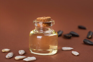 Sunflower oil and sunflower grains on a brown background.