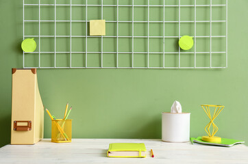 Comfortable workplace with stationery near color wall
