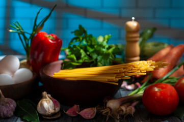 long semolina noodles in a wooden bowl with assorted vegetables eggs on table and light from a window