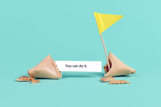 Fortune cookie with motivational text saying 'You can do it' with flag on real blue background