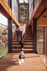 Young girl with her dog walks in a modern park. During the autumn day, enjoy the beautiful weather.