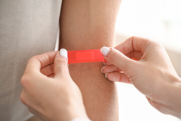 Doctor applying medical patch on patient's arm in clinic, closeup