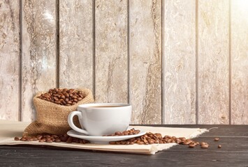 Coffee beans with a cup of hot coffee on wooden desk