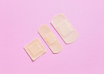 Different medical plasters on pink background
