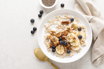 Oatmeal bowl. Oat porridge with banana, blueberry, walnut, chia seeds and almond milk for healthy...