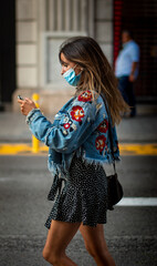 Beauty girl looking at her phone walking on the street with flower jacket and blue covid mask