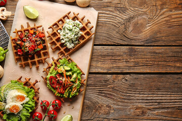 Delicious Belgian waffles with vegetables on wooden background
