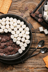 Frying pan with uncooked S'mores dip on wooden background