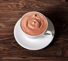
White cup with hot chocolate on a wooden background. View from above.