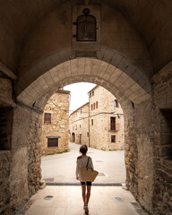 Back girl walking into an old romania architecture in a stone old beautiful town in costa brava