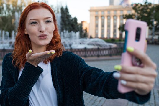 A beautiful, attractive and happy Caucasian girl taking a selfie and showing a kiss.