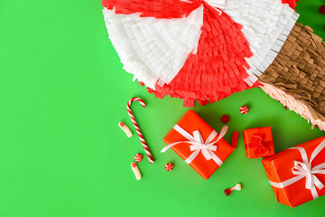 Mexican pinata with candies and gifts on green background