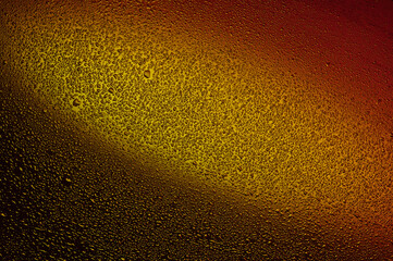Water drops on black glass. Background illuminated with red and yellow ​light.