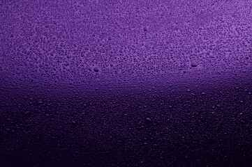 Water drops on black glass. Background illuminated with lilac ​light.