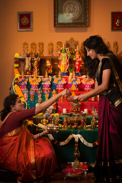 Mother teaching daughter how to do pooja ( sacred offering) 