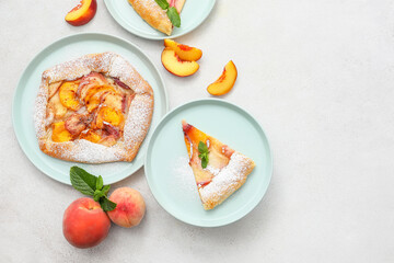 Plates with tasty peach galette on light background