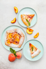Plates with tasty peach galette on light background