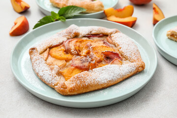 Plate with tasty peach galette on light background, closeup