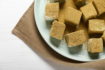Plate with tasty hojicha marshmallows on light wooden background, closeup
