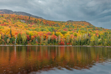 Fototapeta na wymiar Mount Kaaikop in the background with Lac Legault showing the Autumn fall colors in the water reflection, Quebec, Canada.