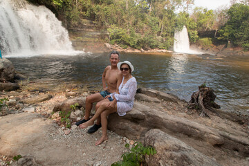 Couple Sitting in Front of the Waterfall known as Gemeas do Itapecuru or the Twins in Chapadas das Mesas, in the State of Maranhao, Brazil, near the City of Carollina