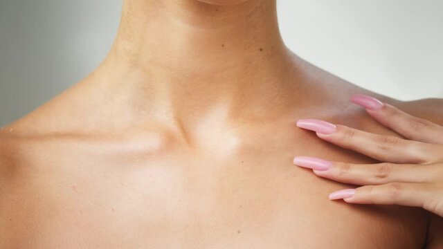 Young woman touching clavicles close-up, model with smooth healthy skin. Female shoulders, naked body. Beauty and body care concept. Unrecognizable person with bare neck and chest on white background.