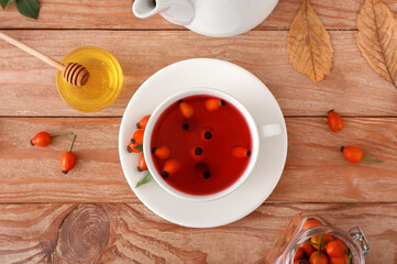 Cup of tasty rose hip tea on wooden background