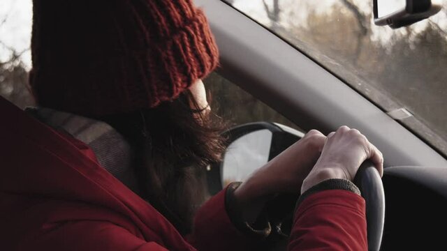 A woman sitting behind the steering wheel of a car is nervous, angry and honking.