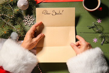 Hands of Santa Claus with empty letter at table