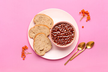 Bowl with tasty rowan jam and bread on color background
