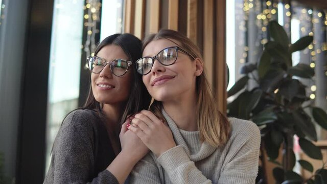Two gay, lesbian happy women in a cafe laughing and hugging while on a romantic lunch date, lgbt, gay and love concept