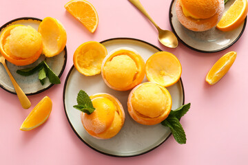 Naklejka na ściany i meble Plates with tasty ice creams in orange peels on color background