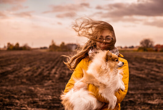 Windy autumn day. Girl with a dog. Long blond hair blowing in the strong wind - gale.