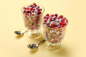 Glass bowls with tasty sugared cranberries on beige background