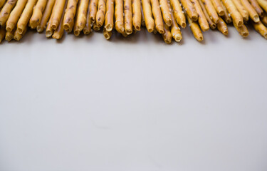 Background from sticks of crackers with salt on a gray background. Food concept. Edible snacks dry sticks with salt. Texture from straws, crackers sticks.